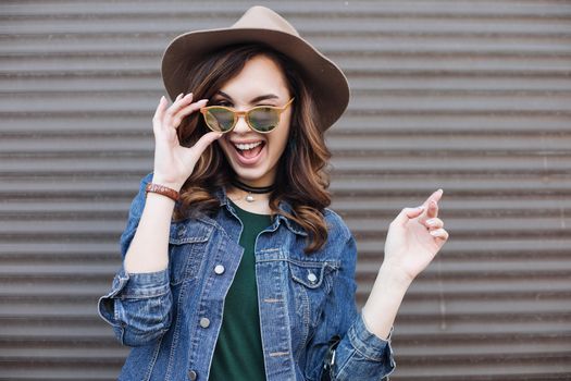 Romantic and beautiful brunette girl in brown hat lokking at camera and posing at street. Attractive woman with wavy hair, perfect make up, walking after beauty salon. Street fashion.