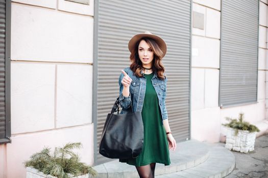 Beautiful positivity brunette woman in hat, white blouse, jeans walking at sunset in city, after shopping and beauty salon. Smiling fashionable girl stylish wearing posing at camera. Hipster look.