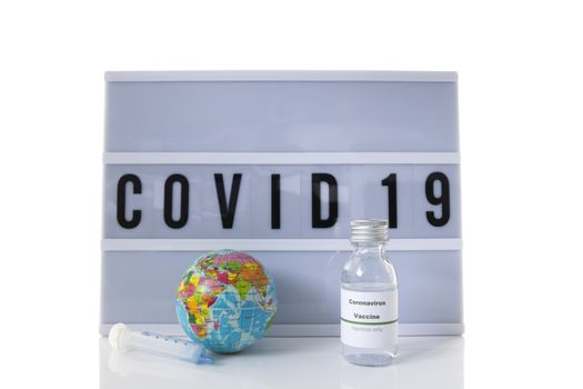 covid 19 on text display wisolated on white background and world globe and vaccine