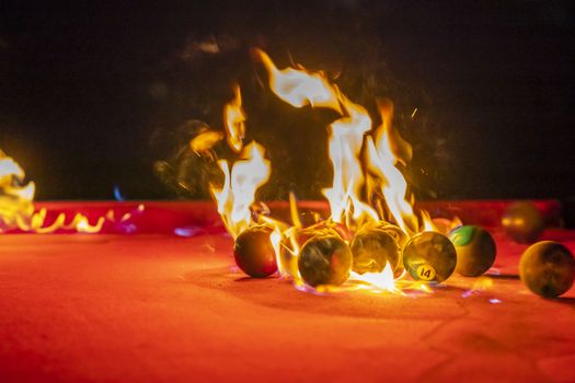 Billiard balls are photographed on fire while sitting outdoors in an open environment