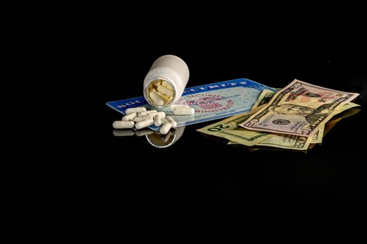 A bottle of pills on top of a blank social security card surrounded by American money