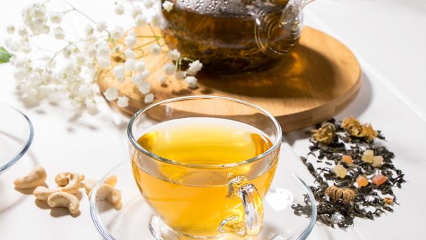 A Cup of green tea and a teapot. Flower tea with fruit slices. Tea ceremony, traditional drink. Afternoon tea, homelike. Flat lay. Oriental, cozy, preparation, heat, tradition, japanese, leafy, herbal