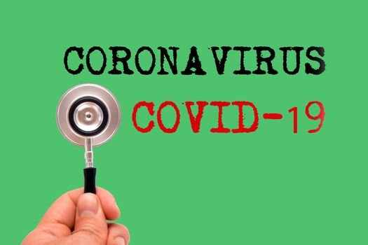 Stethoscope with Coronavirus and COVID-19 words on green background background.
