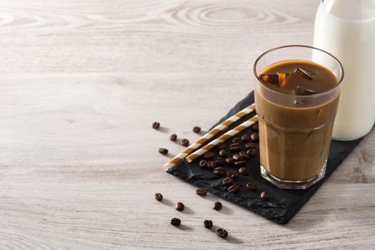 Iced coffee or caffe latte in a tall glass on wooden table