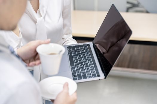 Portrait of two business looking at laptop and working in office. Young business colleagues discussing work in the office.