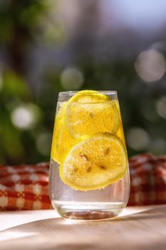 Lemonade with fresh lemon in glass on garden background