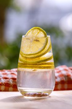 Lemonade with fresh lemon in glass on garden background