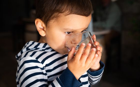 Cute little boy drinking water from a glass