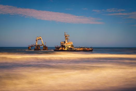 Abandoned shipwreck of the stranded Zeila vessel at the Skeleton Coast near Swakopmund in Namibia, Africa, with many cormorants sitting on the wreck. Long exposure.