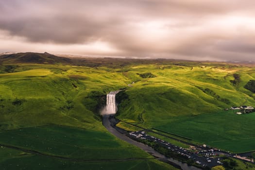 Aerial view of the Skogafoss waterfall in southern Iceland at sunset surrounded by beautiful Icelandic landscape.