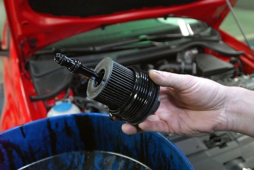 Repairman holding the old oil filter by car