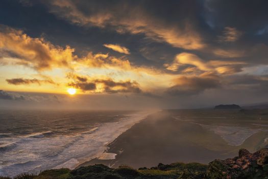Dramatic and stormy sunset above a black beach viewed from Dyrholaey viewpoint in Iceland.