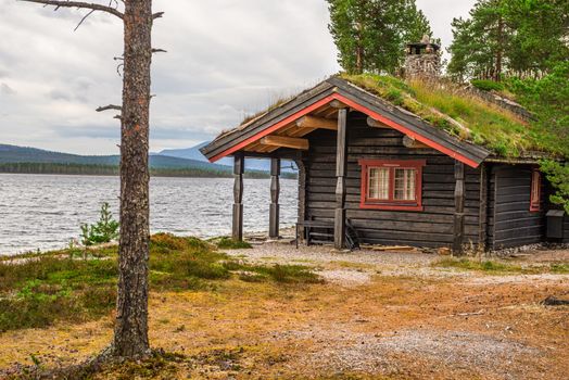 Cabin with turf roof with a lake in the background in Norway.