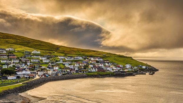 Sunrise above the village of Sandavagur with heavy clouds, Faroe Islands, Denmark. Hdr processed.