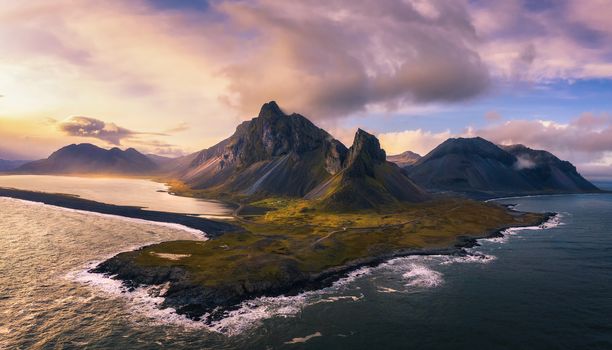 Aerial View of the Eystrahorn with Krossanesfjall Mountain and a nearby black sand beach in Iceland at sunset.