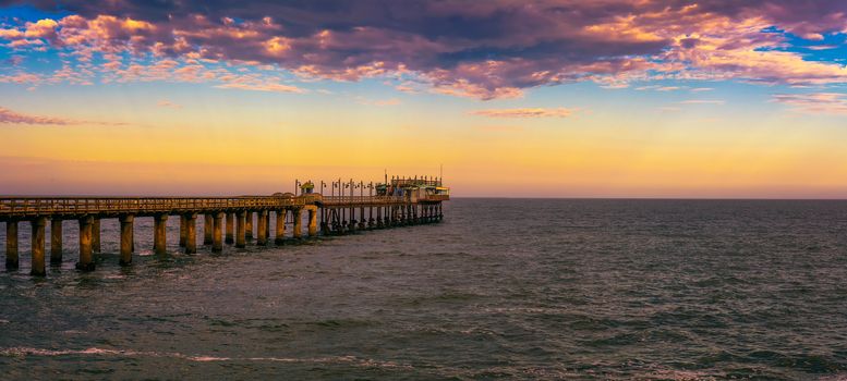 Colorful sunset over the old historic jetty in Swakopmund, Namibia. Swakopmund is situated in the Namib Desert and is the fourth largest population centre in Namibia.