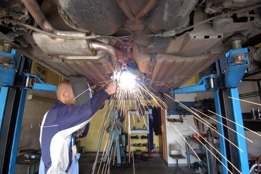 welder working under the car