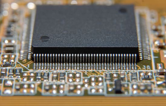 Electronic chip on circuit board. Macro, shallow DOF.