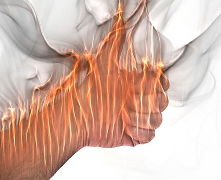 A human hand on fire burning with orange flames and some smoke in front of a white background