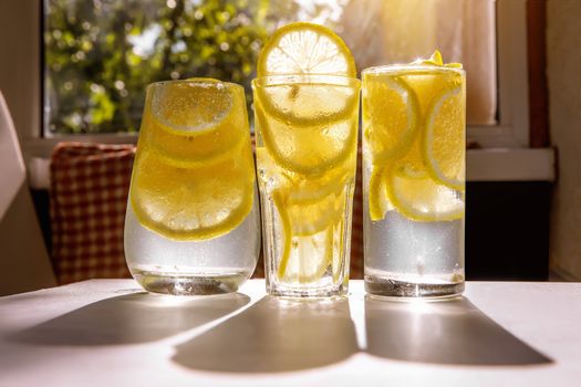 Three glasses of lemon water on the sunny room background