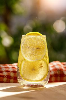 Lemonade with fresh lemon in glass on garden background