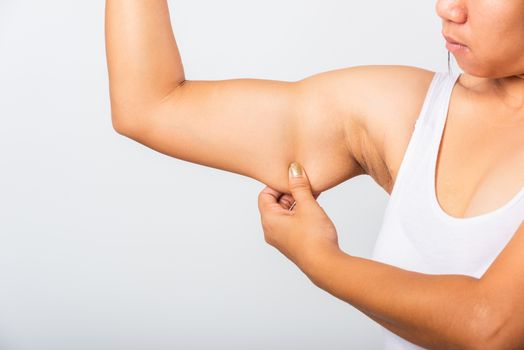 Close up of Asian woman pulling excess fat on her under arm, problem armpit skin, studio isolated on white background, Healthy overweight excess body concept