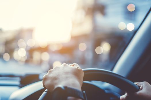 Hand of woman on steering wheel drive a car with sunlight background.