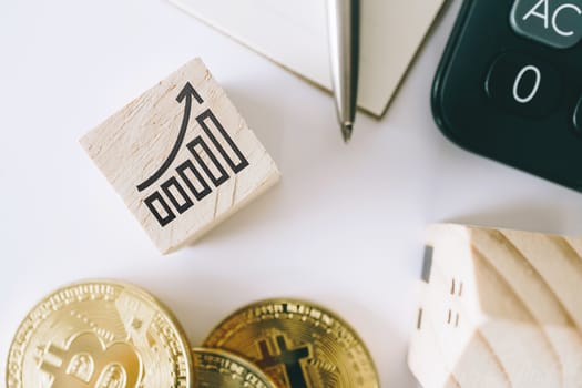 Graph rising up growht exponencial sign on wooden cube with objects such as gold coin, calculator and mini home model behide white clean background. Business financial loan property concept.