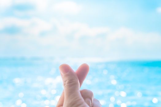 Love symbol of korean with your fingers. A female hand depicts a heart in front of beautiful nature. 