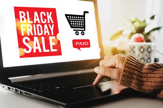 Women hand using computer shopping big sale in black friday online with cart, dollar icons on laptop screen. Social media maketing technology concept.