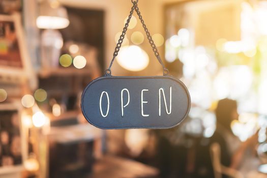 A business sign that says open on cafe or restaurant hang on door at entrance. Vintage color tone style.