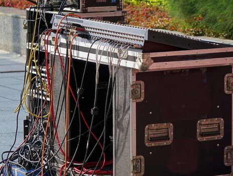 A large audio mixer console with a multitude of cables attached
