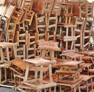 A street vendor is offering a large pile of sturdy bamboo stools
