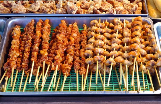 Pieces of chicken meat cooked on bamboo skewers at a food stall