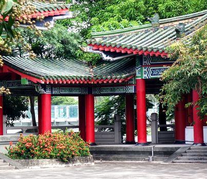 A quiet temple courtyard with red columns and green roof tiles
