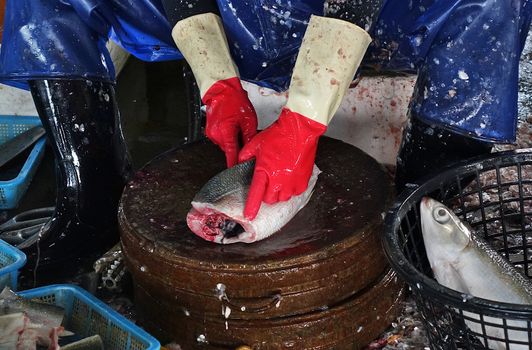 A fishmonger in Taiwan cleans fish at a local wet market.
