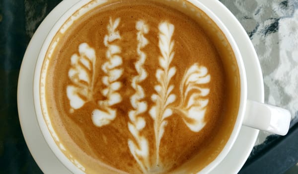 A cup of latte coffee with a floral art design