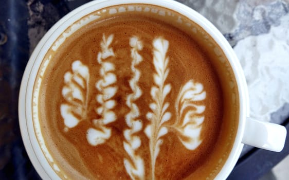 A cup of latte coffee with a floral art design
