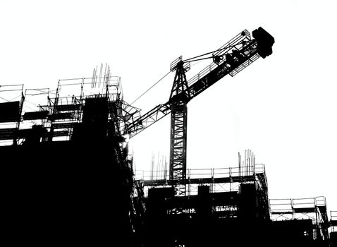 Construction site with crane and scaffolding seen as a silhouette