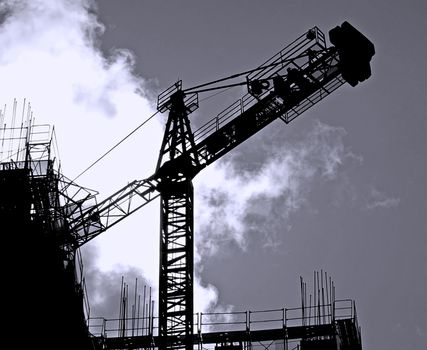 Construction site with crane and scaffolding seen as a silhouette