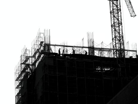 Construction site with crane and scaffolding seen as a silhouette