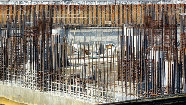 A large scale construction site with steel bars and concrete pillars
