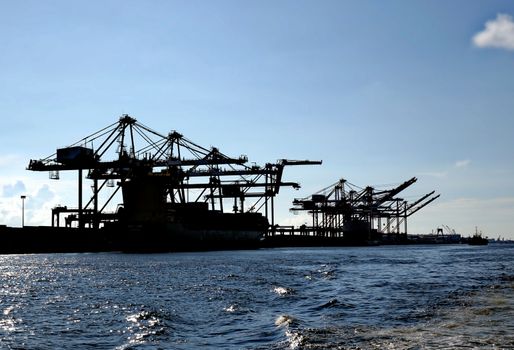A large container loading facility with gantry cranes seen in silhouette