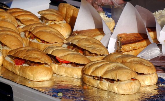 A street vendor sells sandwiches with roasted meat, tomatoes and pickles
