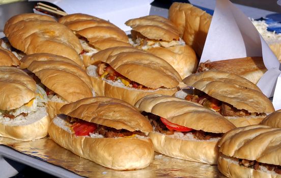 A street vendor sells sandwiches with roasted meat, tomatoes and pickles