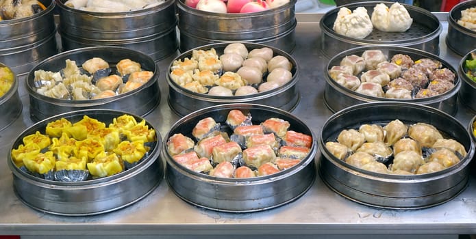 An outdoor vendor sells Cantonese Dim Sum dishes cooked in metal steamers