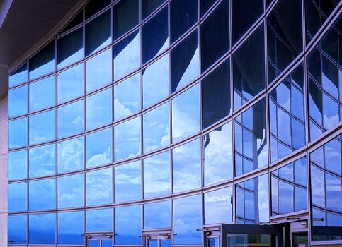 A modern corporate building with a curved facade reflecting the sky
