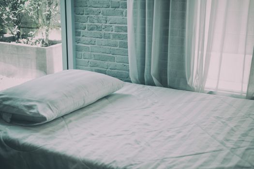 white pillow on mattress bed beside see through sheer window curtain