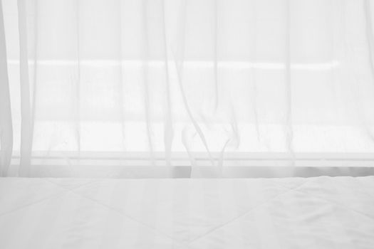 white mattress bed beside see through sheer window curtain