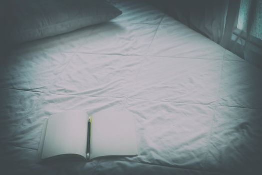 opening notebook & pencil on white bed mattress